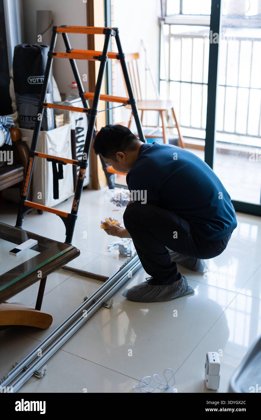 Man installing sliding glass door frame in modern apartment, Shanghai, China Stock Photo