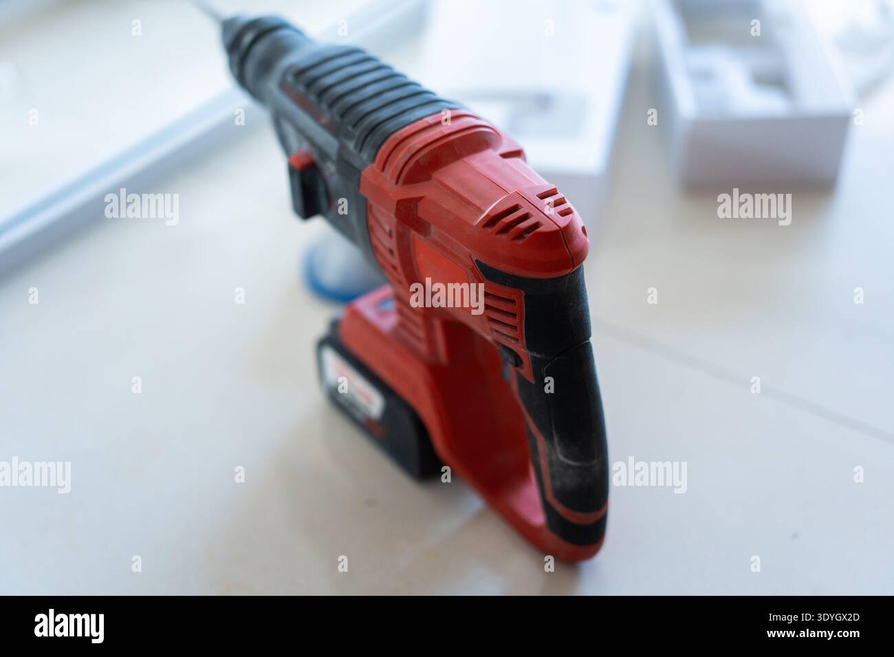 Cordless hammer drill on white workbench in workshop with tool box in background Stock Photo