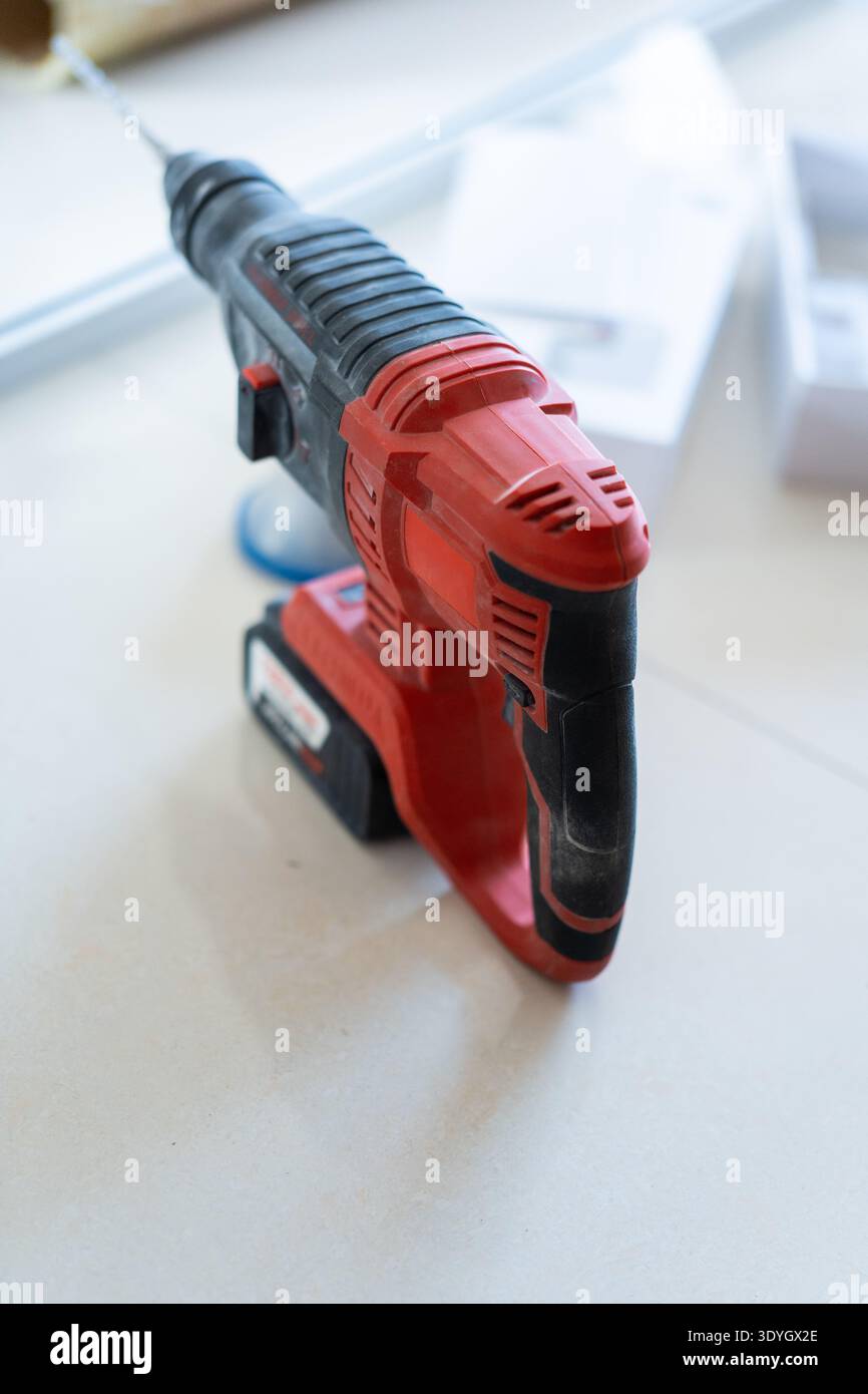 Red and Black Cordless Hammer Drill on White Surface in Workshop Setting Stock Photo
