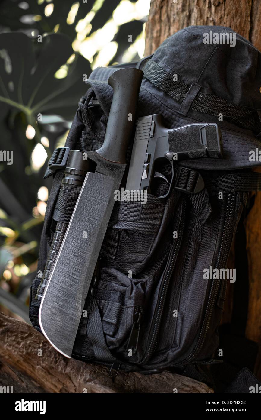 machete knife and a hiking backpack rest on a log. Stock Photo