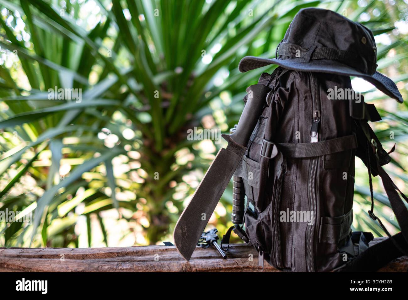 machete knife and a hiking backpack rest on a log. Stock Photo