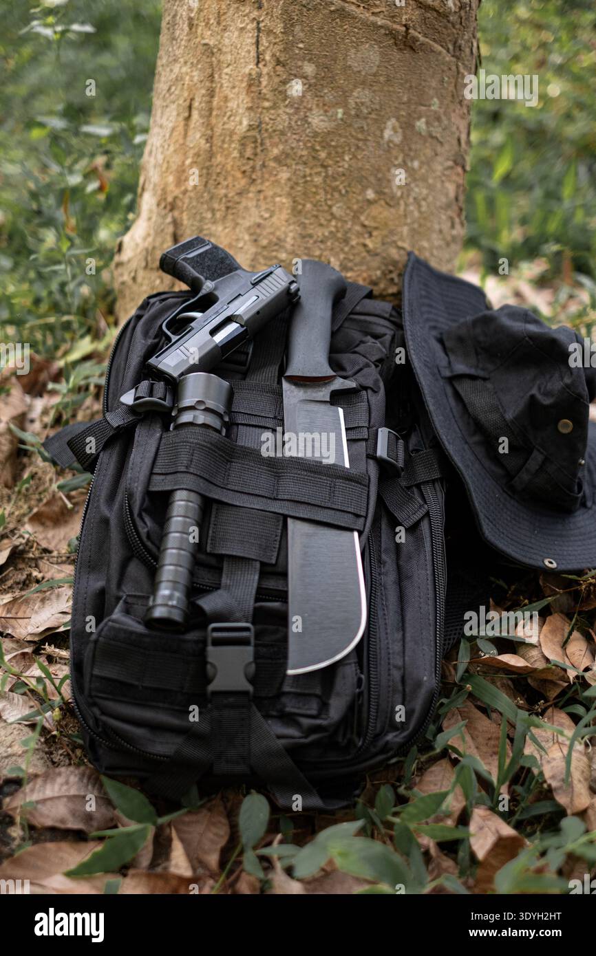 machete knife and a hiking backpack rest on a log. Stock Photo