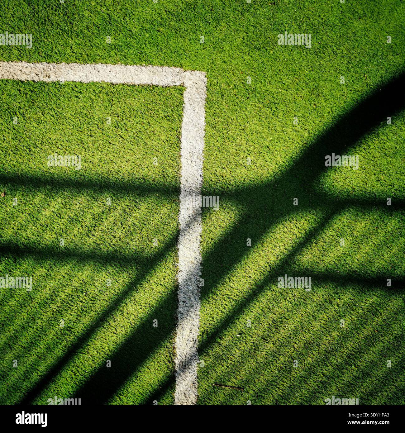 Green artificial grass covers a sports field with a crisp white boundary line in the lower right corner. - Smartphone Captured Stock Image