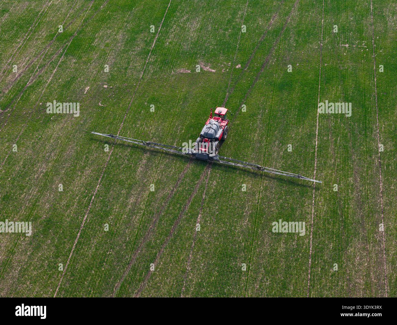 Aerial drone view of agricultural machinery spraying the field and working the land Stock Photo