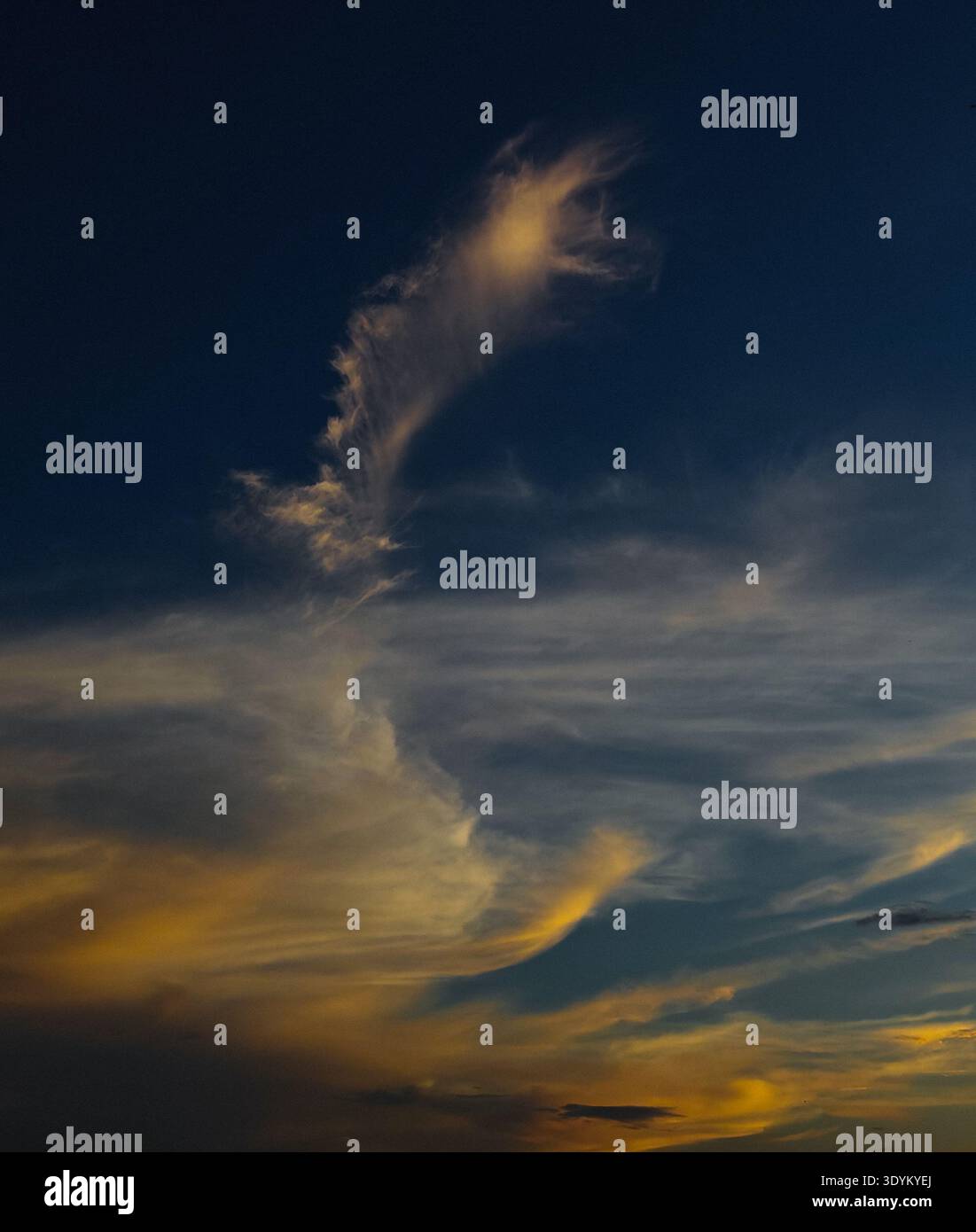 Feather like cloud during evening with orange white colored shade. Stock Photo