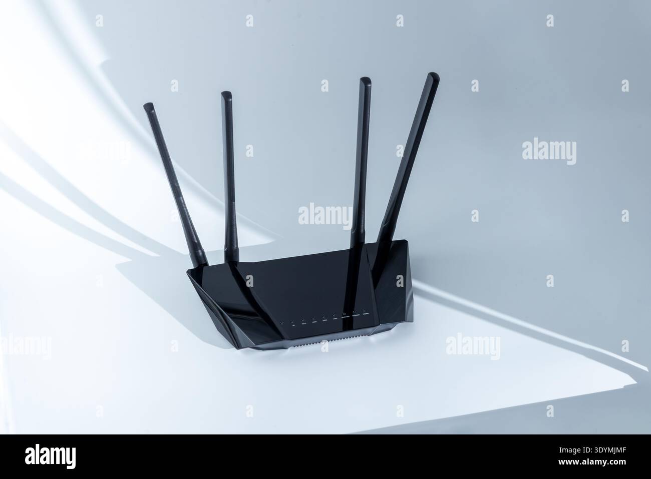 Wireless WiFi router with four antennas on white surface casting shadows representing modern internet networking device Stock Photo