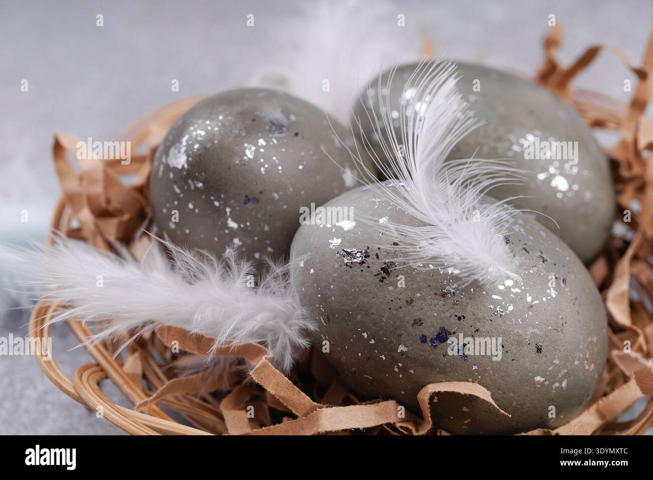 Close up Easter eggs with feathers in wicker nest Stock Photo