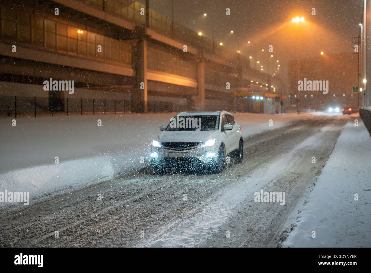 Heavy snowfall and blizzard in city, car driving through roads covered ...