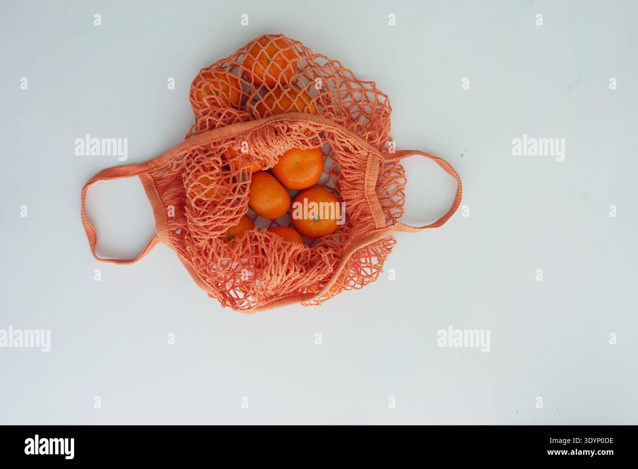 Oranges in a net bag on a light background Stock Photo