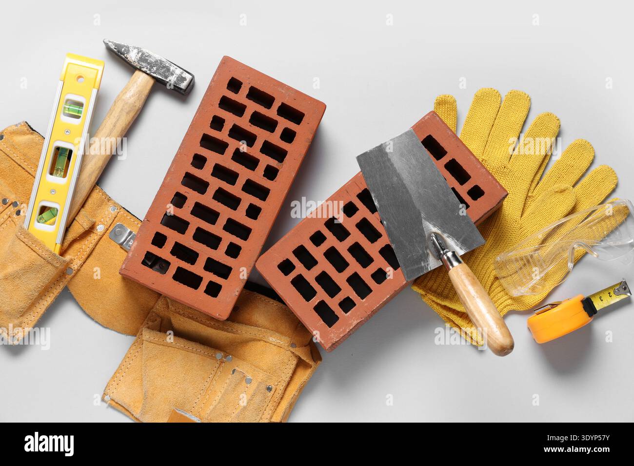 Bricks with builder belt and different tools on white background Stock Photo