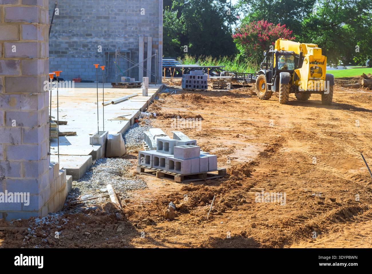 Workers are using heavy machinery arranging building materials at construction site Stock Photo