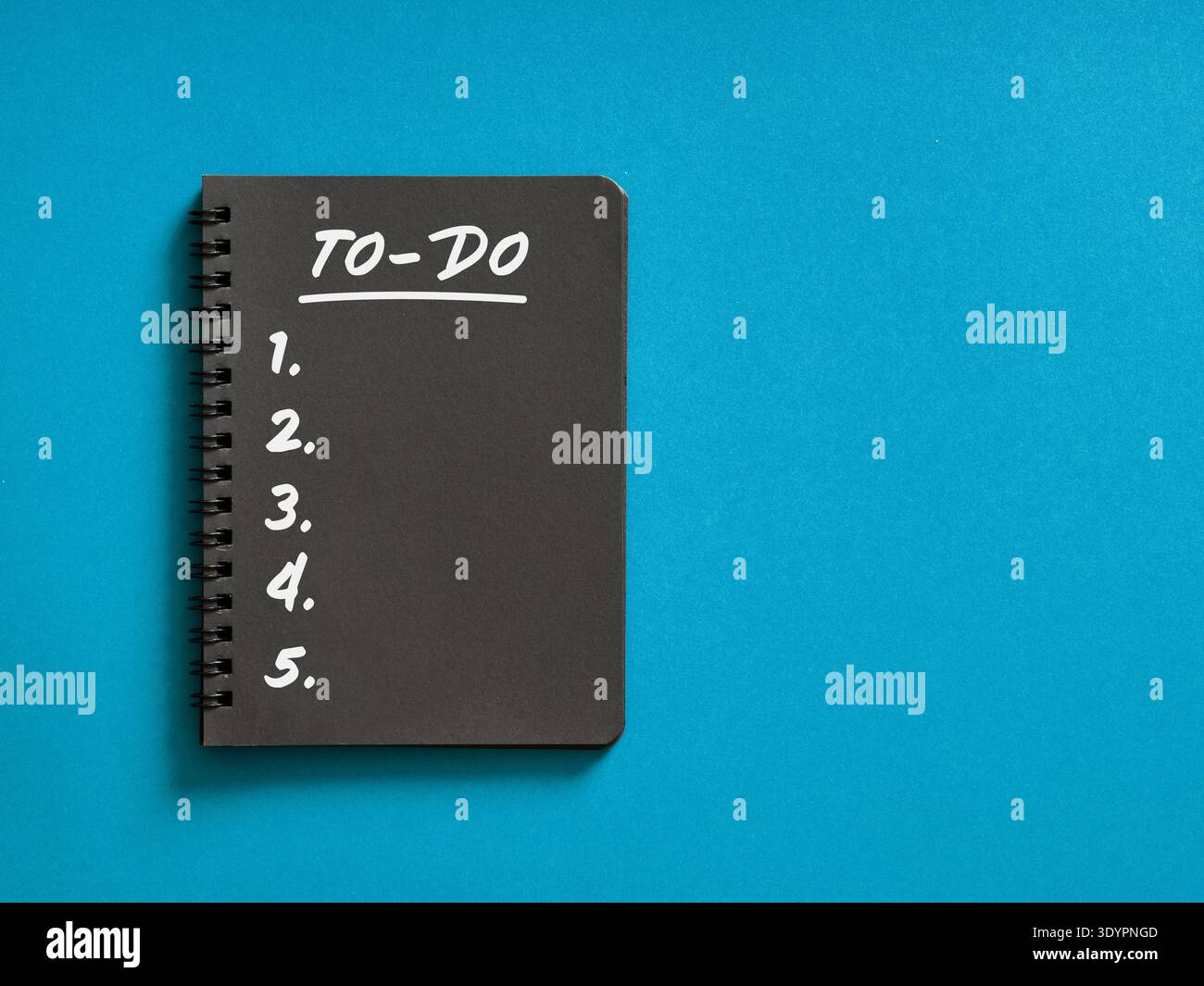 Black spiral notebook displaying a handwritten to do list with numbered items, symbolizing planning, productivity, and task management Stock Photo
