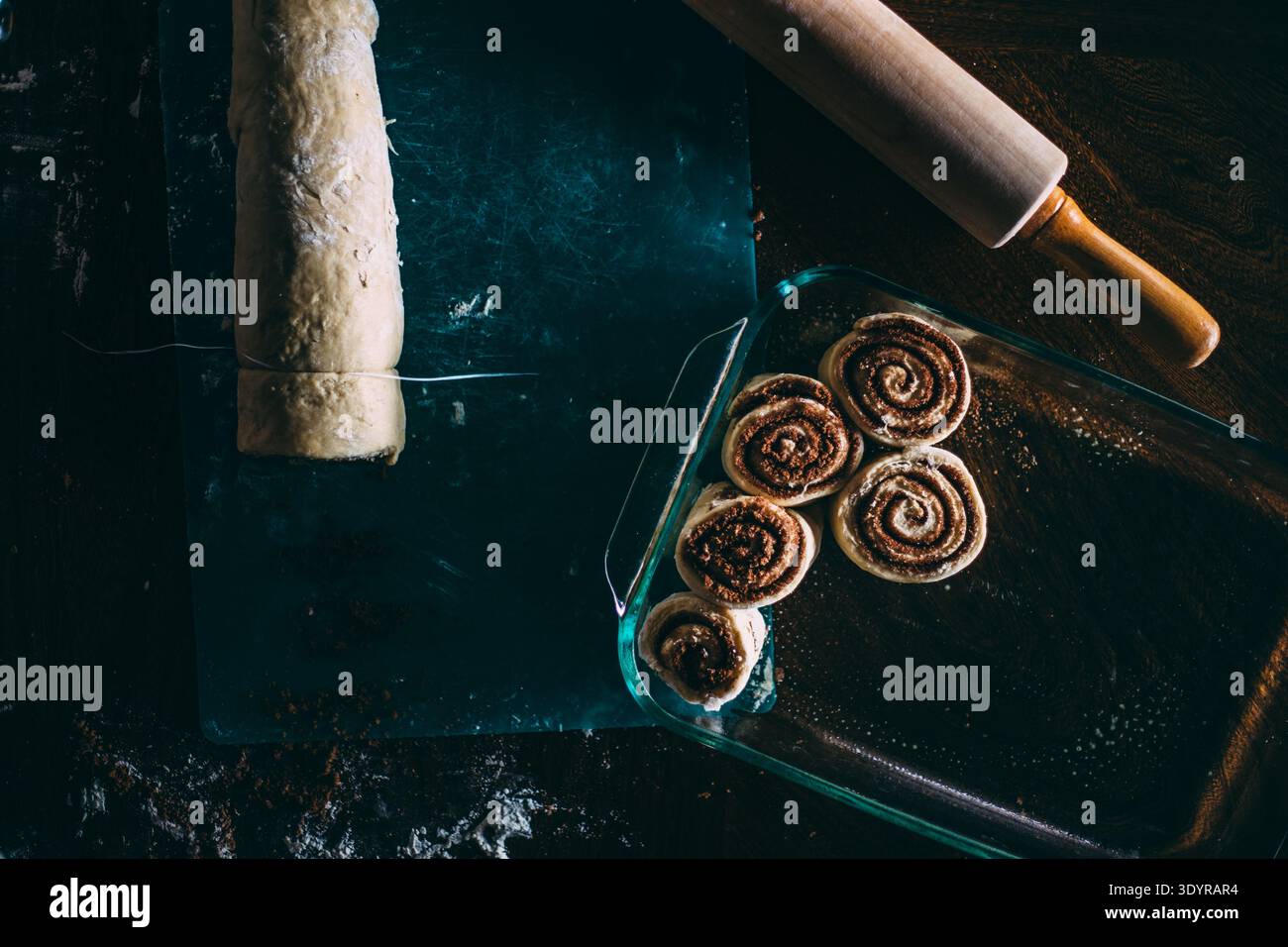 Cinnamon Rolls Getting Sliced and Placed Stock Photo