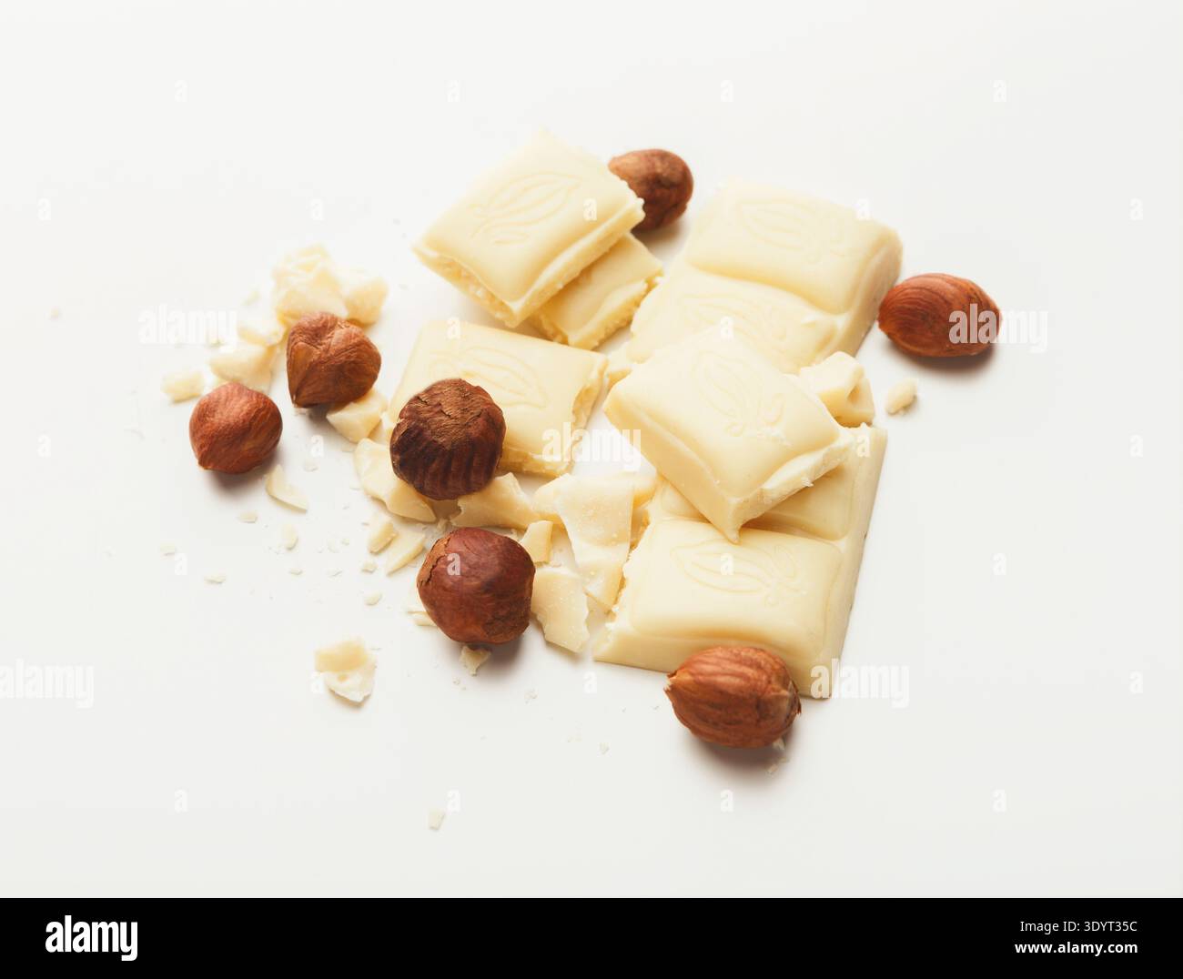 Broken white chocolate bar and hazelnuts isolated Stock Photo