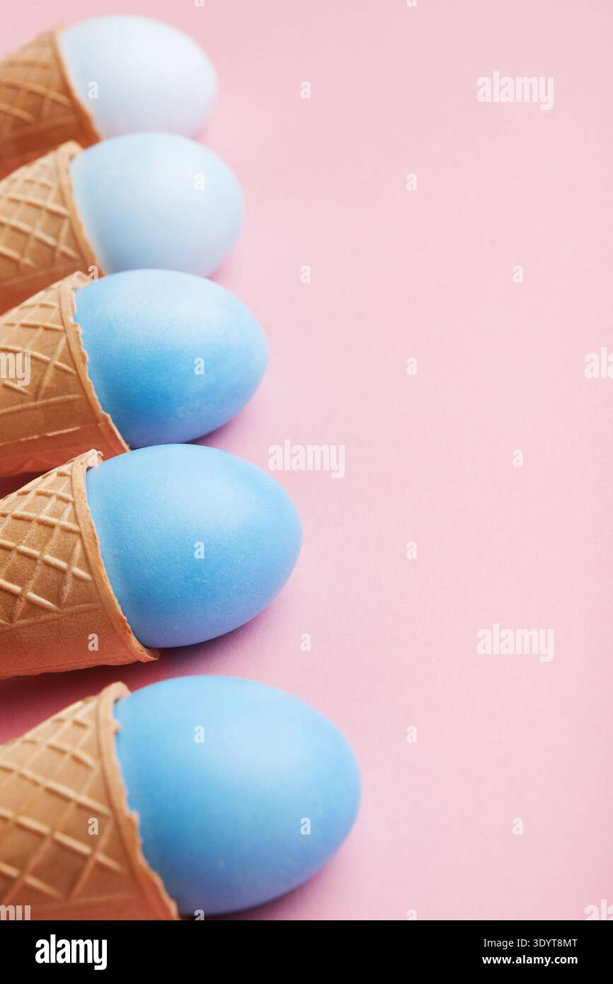 Blue easter eggs in waffle cones on pink background Stock Photo