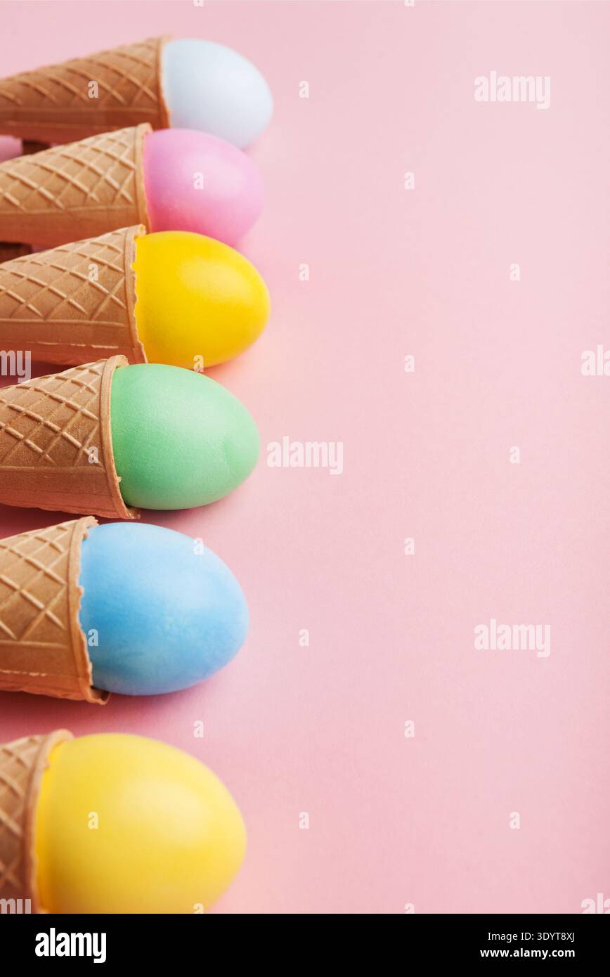 Colorful easter eggs in waffle cones on pink background Stock Photo