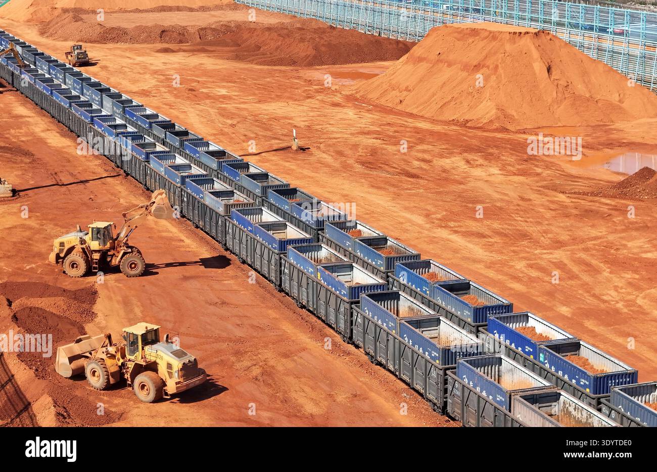 Loaders load imported bauxite ore onto a cargo train, ready to be ...