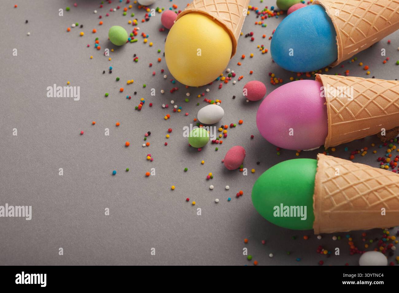 Colorful easter eggs in waffle cones on gray background Stock Photo