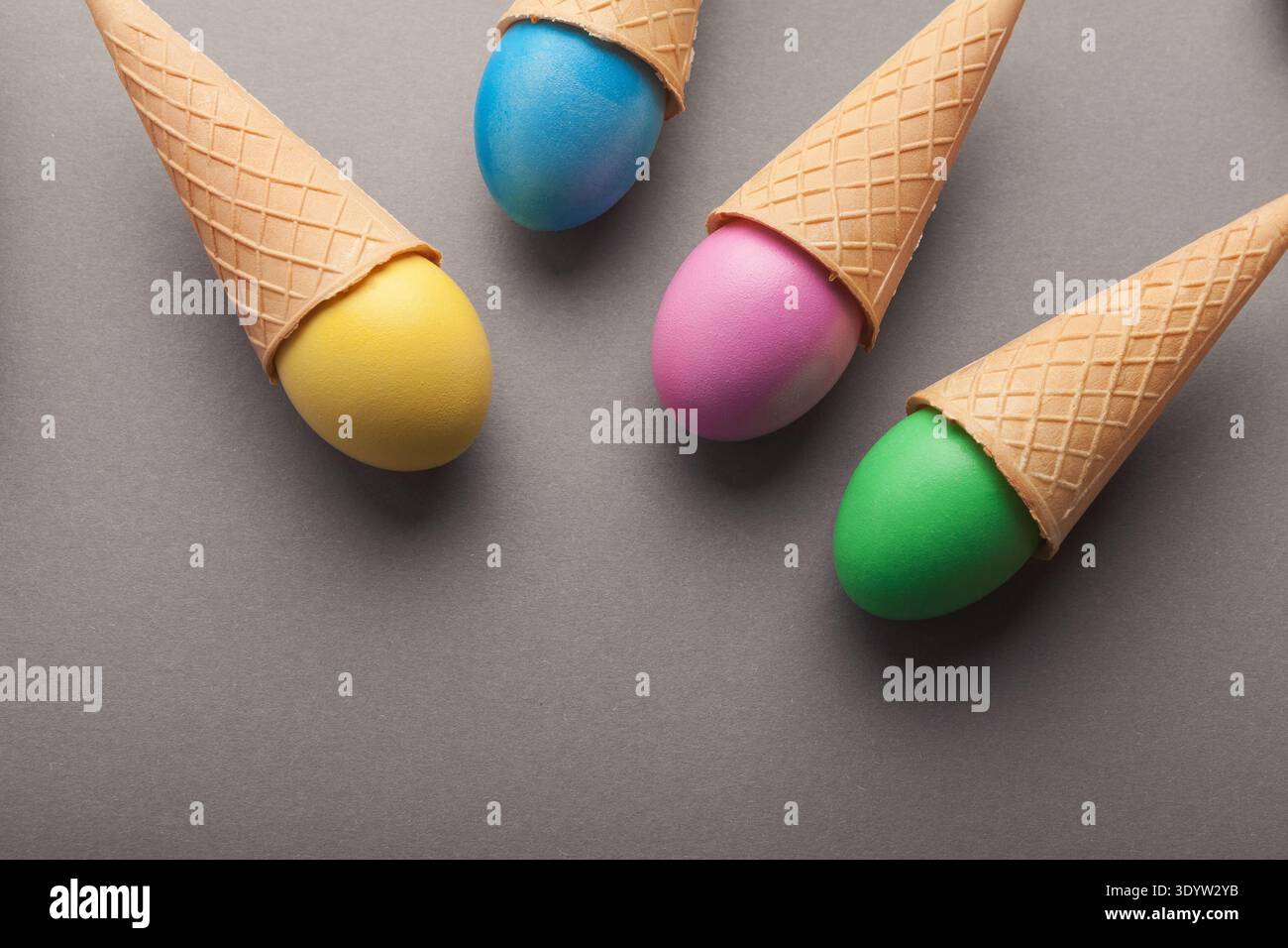 Colorful easter eggs in waffle cones on gray background Stock Photo
