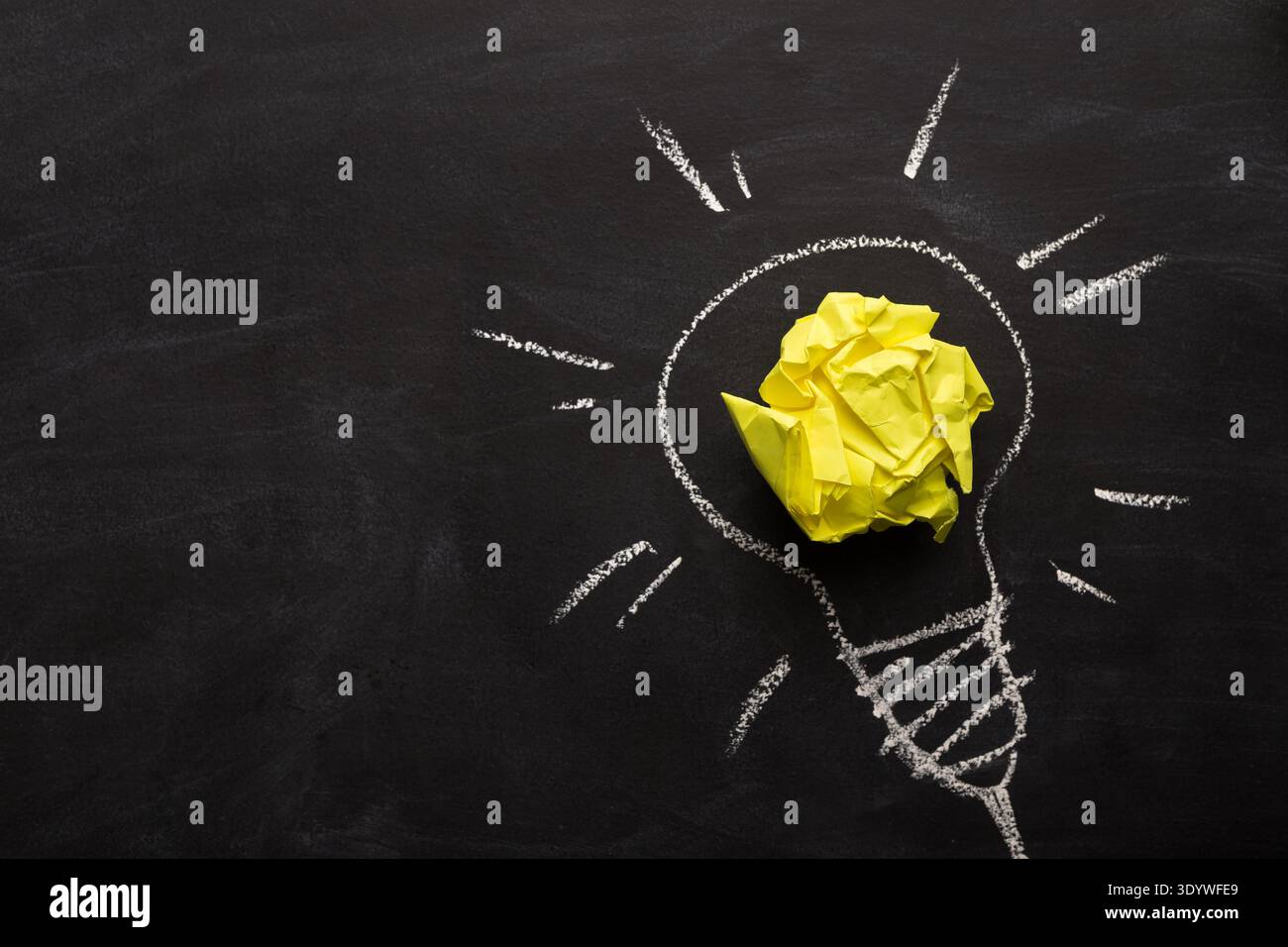 Electric bulb drawn on chalkboard with yellow paper for glowing light Stock Photo