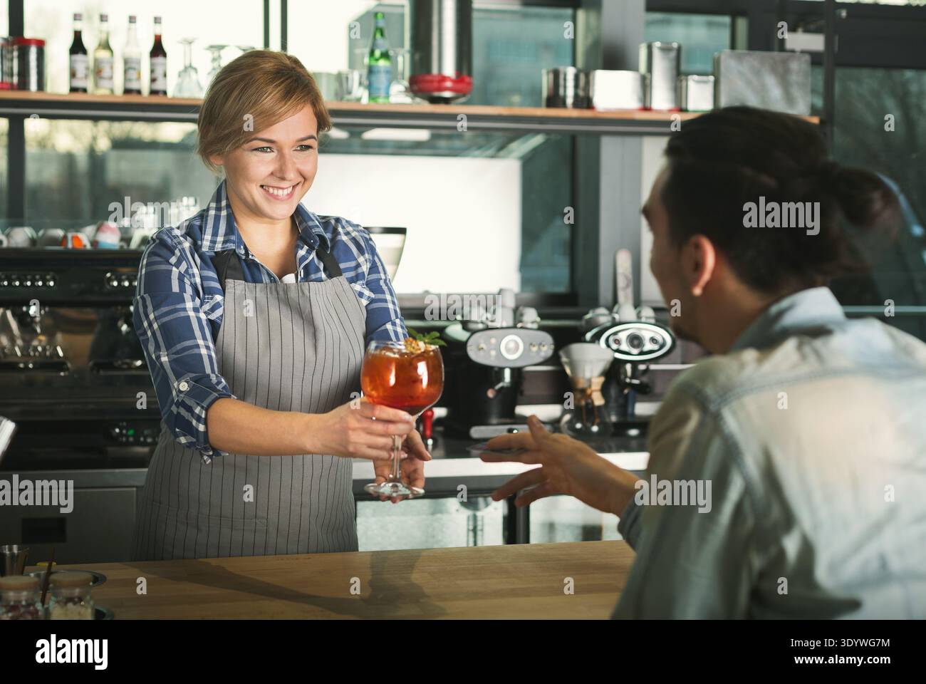 Smiling barista taking payment from client Stock Photo