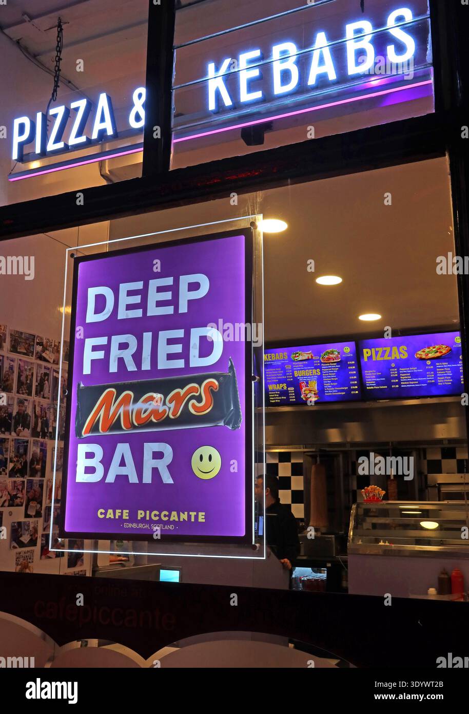 Deep Fried Mars Bar sign in the window of Café Piccante takeaway on Broughton Street, Edinburgh, Scotland, at night with neon “Pizza & Kebabs”. Stock Photo
