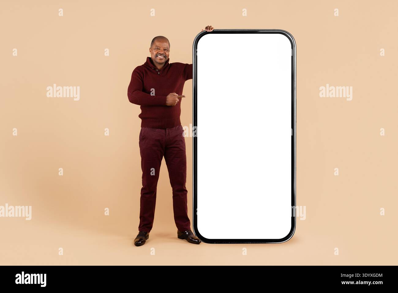 Black man standing beside oversized smartphone mockup and pointing to blank screen Stock Photo