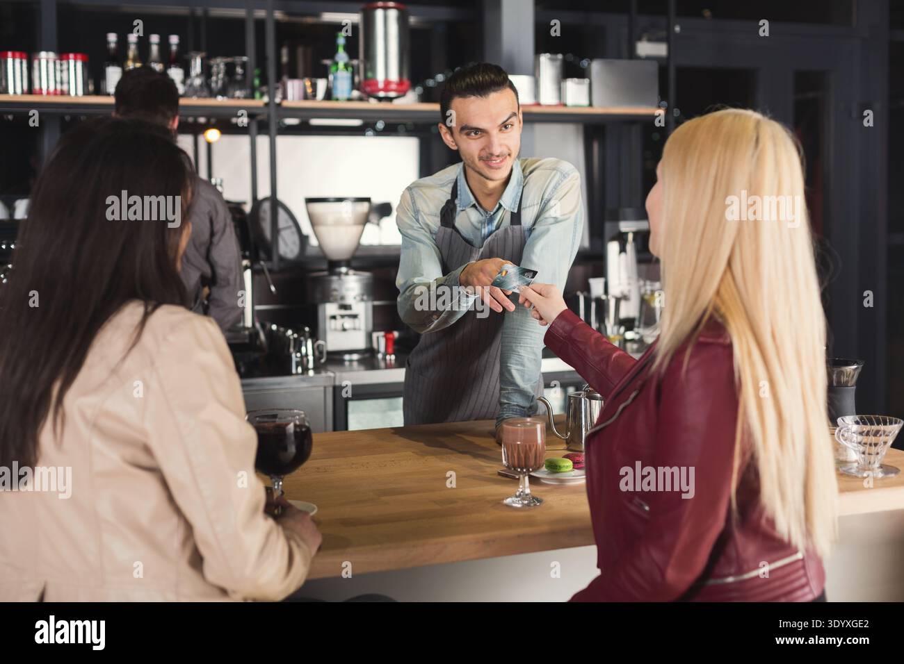 Smiling barista taking payment from clients Stock Photo