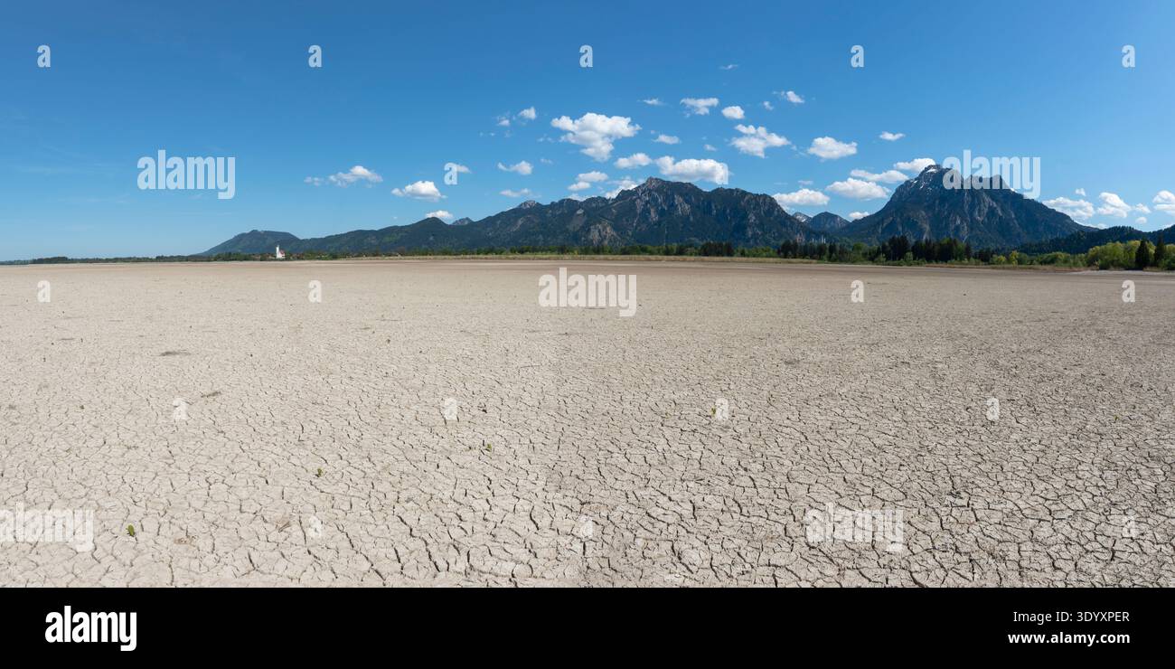 Cracked, dried-out ground, waterless Forggensee in spring, behind it ...