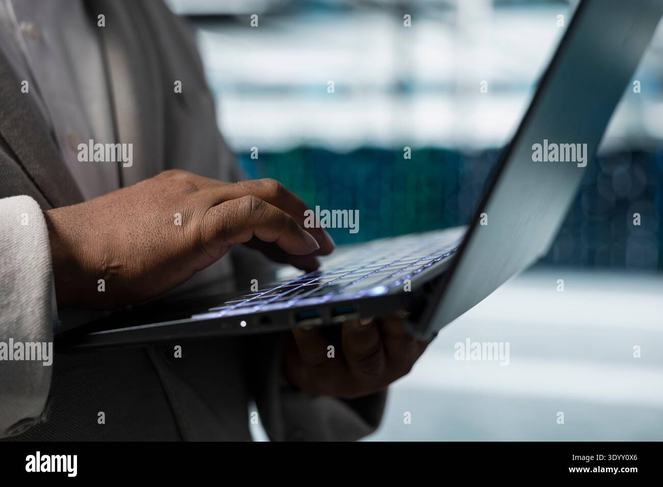 Close up of data center admin using laptop to update systems, protecting servers from easily exploitable software vulnerabilities. Employee using notebook, looking for errors slowing down servers Stock Photo