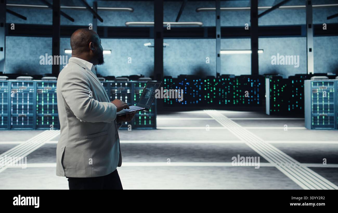 Server room system administrator using laptop to do infrastructure AI machine learning automatization. IT expert in high tech data center doing maintenance using artificial intelligence, camera A Stock Photo