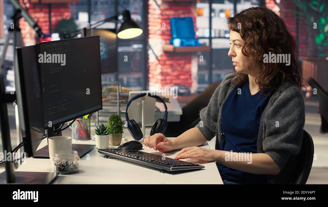 Woman IT developer using pc setup for artificial intelligence cloud computing through self learning algorithms. Agency system engineer works with AI deep neural networks on desktop. Camera B. Stock Photo