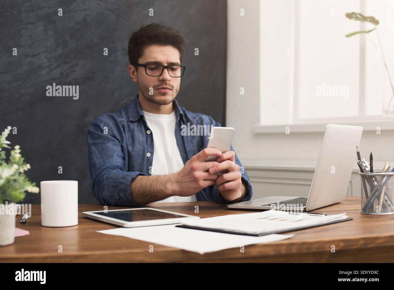 Serious young businessman using mobile in office Stock Photo