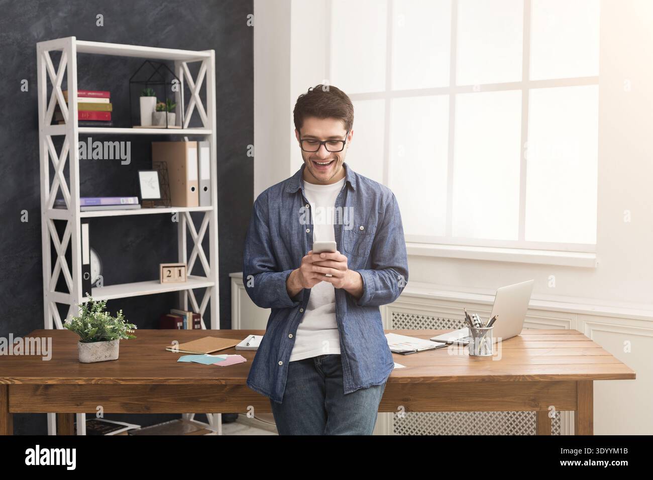 Relaxed young businessman using mobile in office Stock Photo
