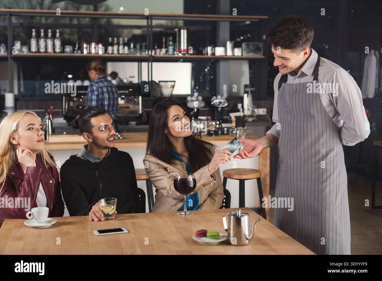 Smiling waiter taking payment from client Stock Photo