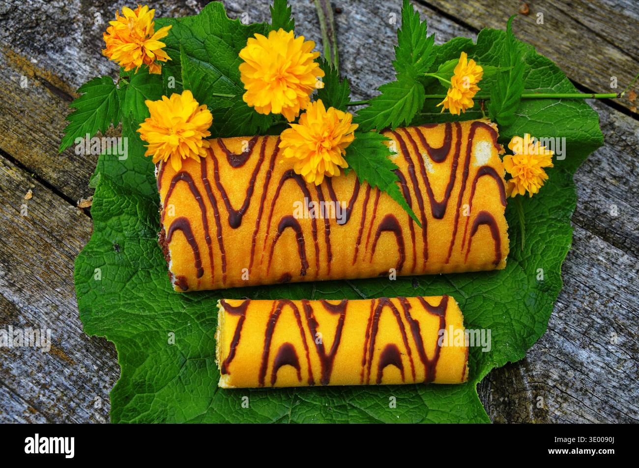 Attractive roll in chocolate and flowers. Stock Photo