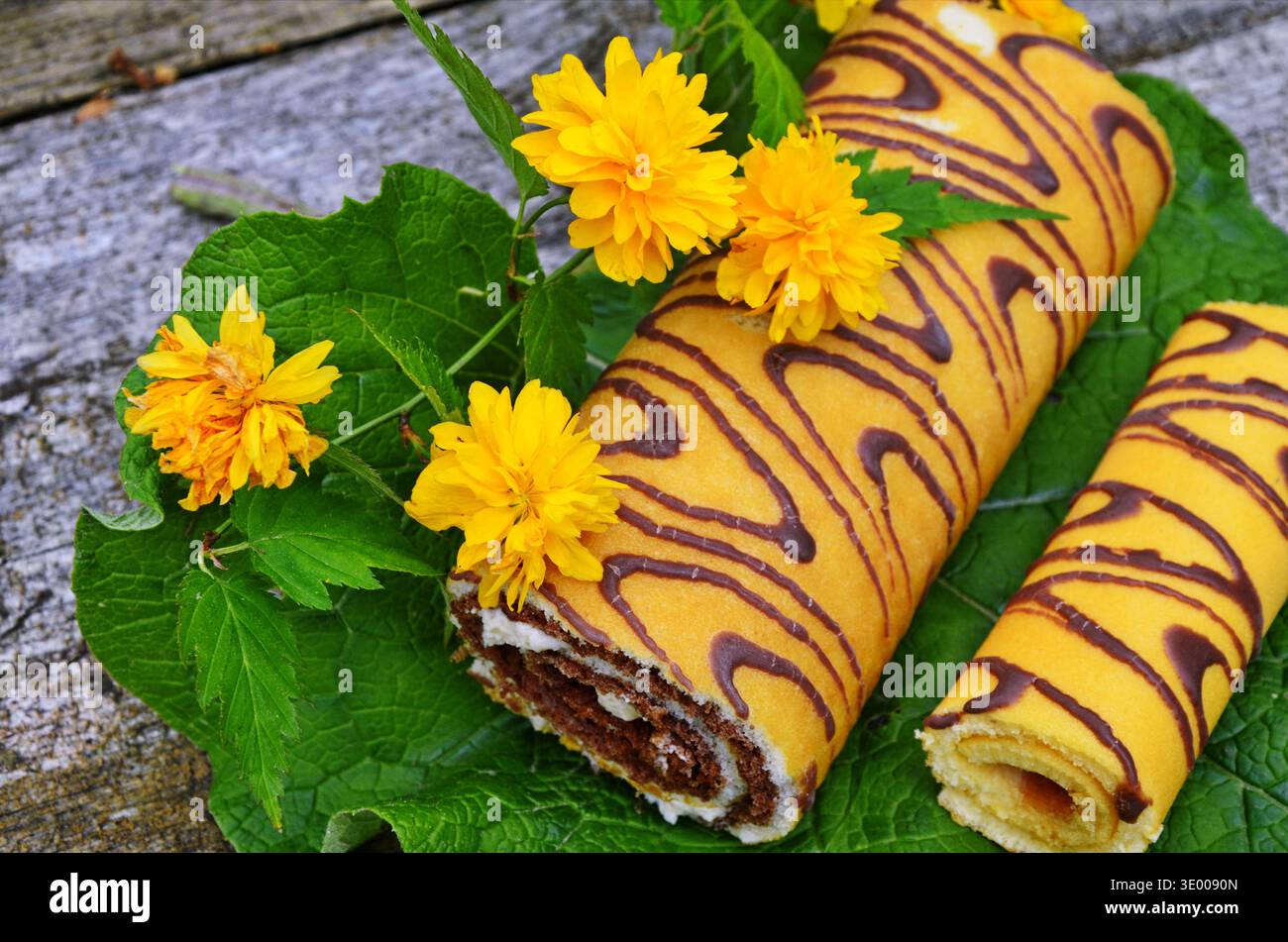 Attractive roll in chocolate and flowers. Stock Photo