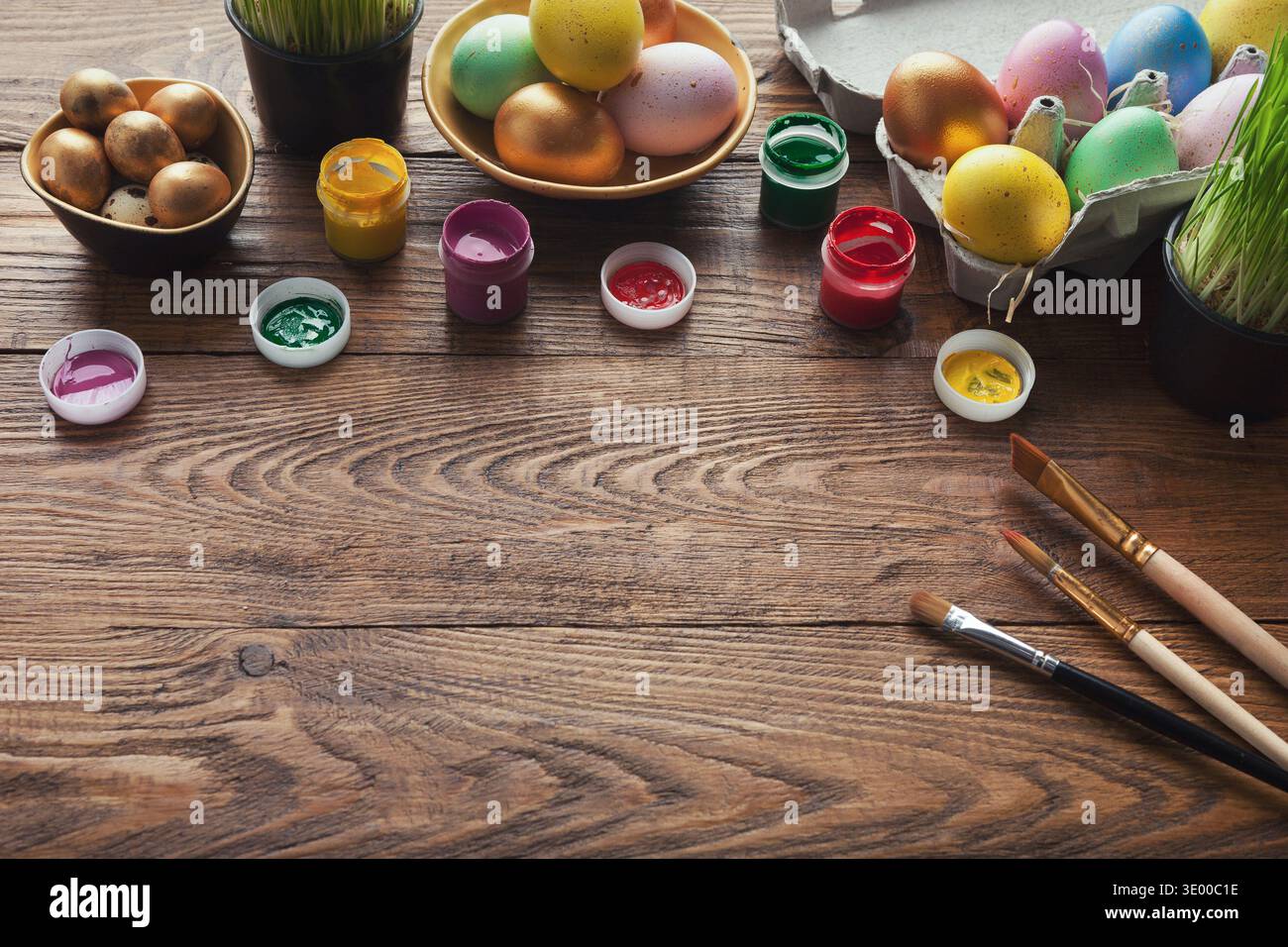 Colorful easter eggs and brushes on wooden table Stock Photo