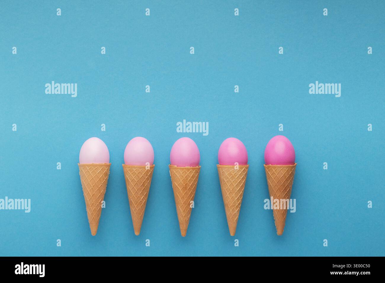 Pink easter eggs in waffle cones on blue background Stock Photo