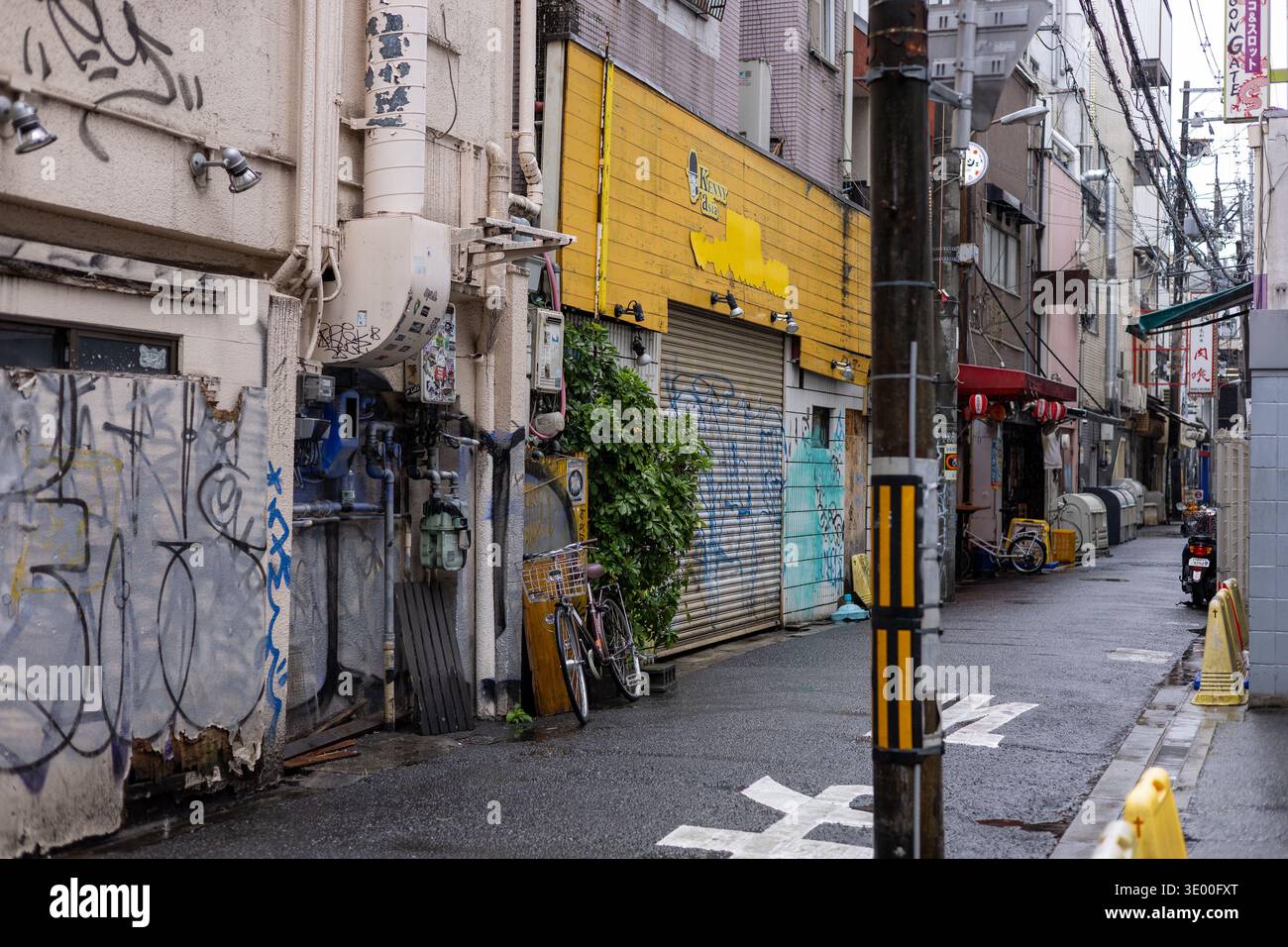 A gritty back alley with graffiti, closed shutters and bicycles in