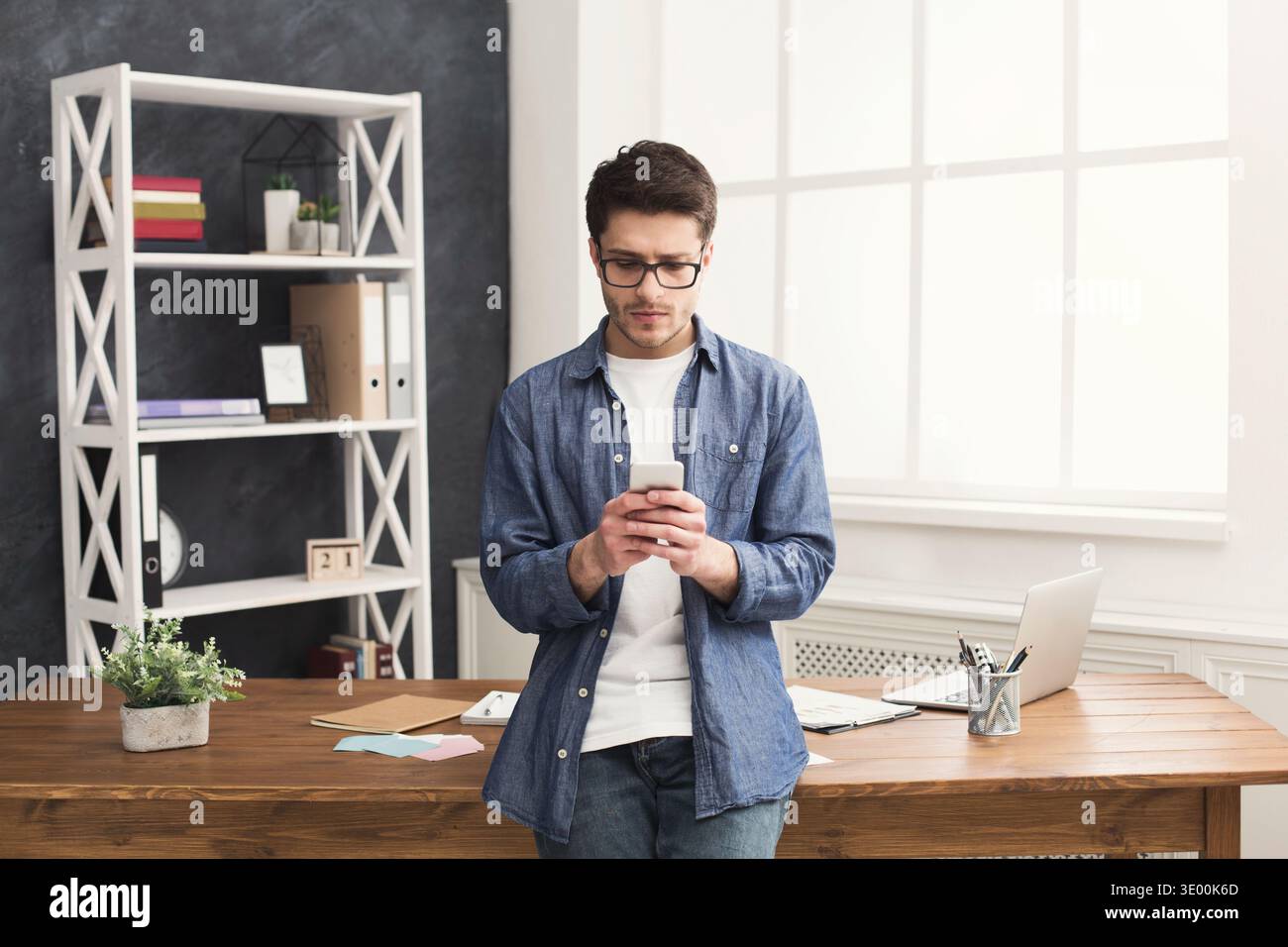 Serious young businessman using mobile in office Stock Photo