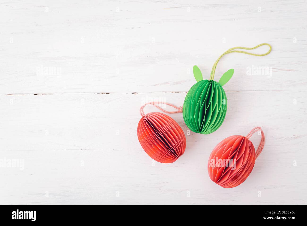Colorful paper Easter eggs decorations on white wooden background. Top view, flat lay, copy space. Stock Photo