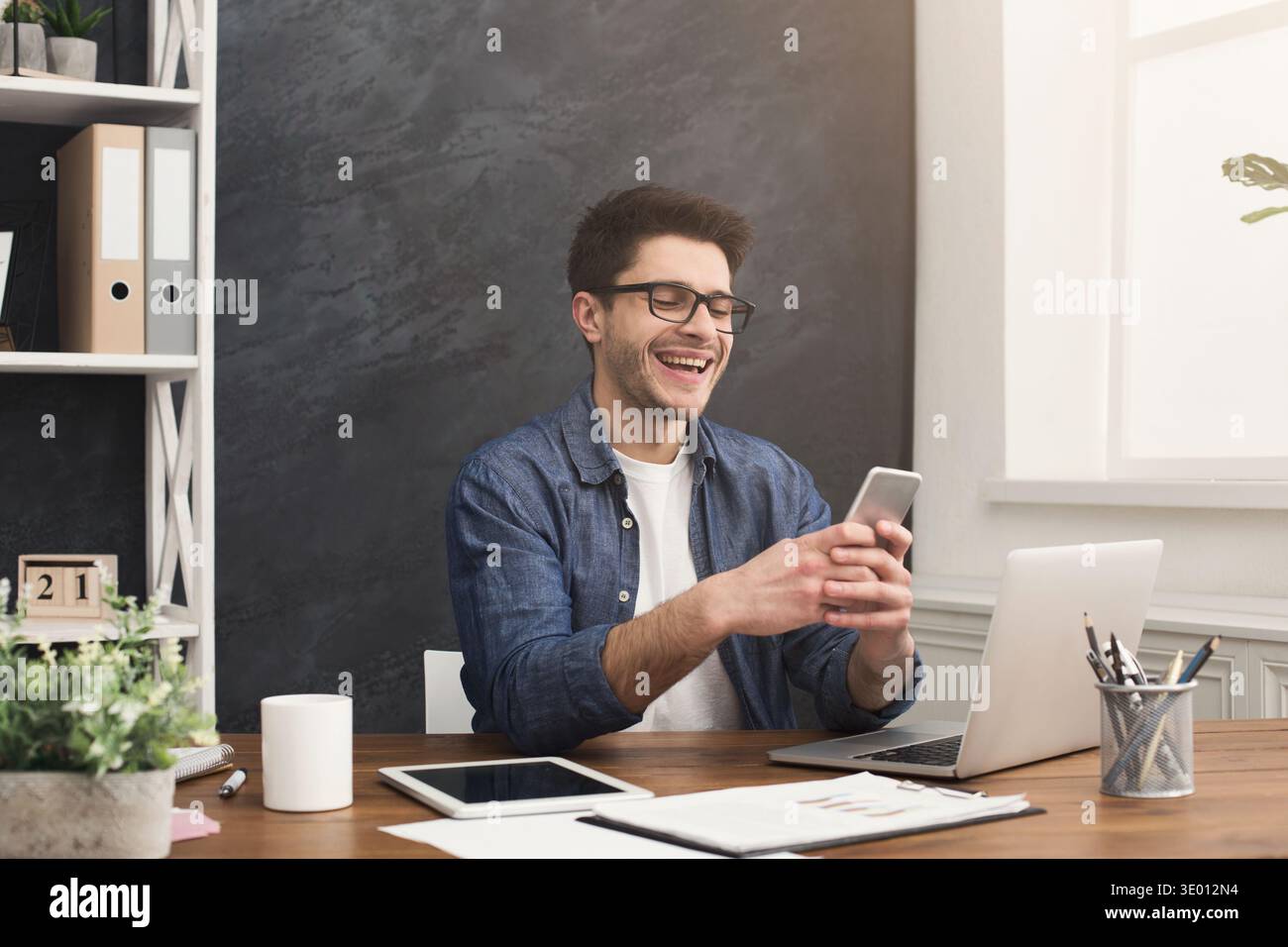 Relaxed young businessman using mobile in office Stock Photo