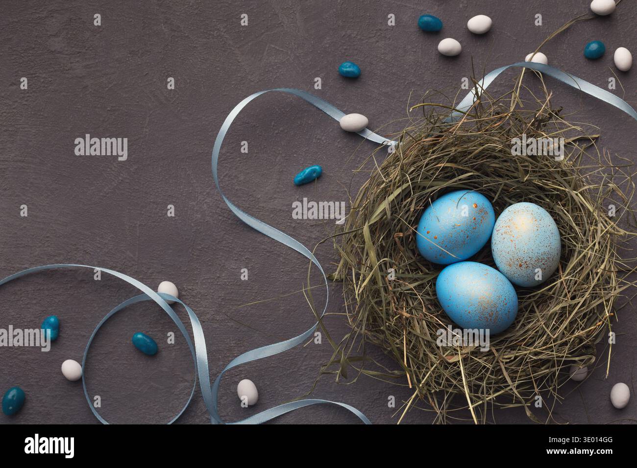 Easter background. Colored eggs in nest on gray stone surface Stock Photo
