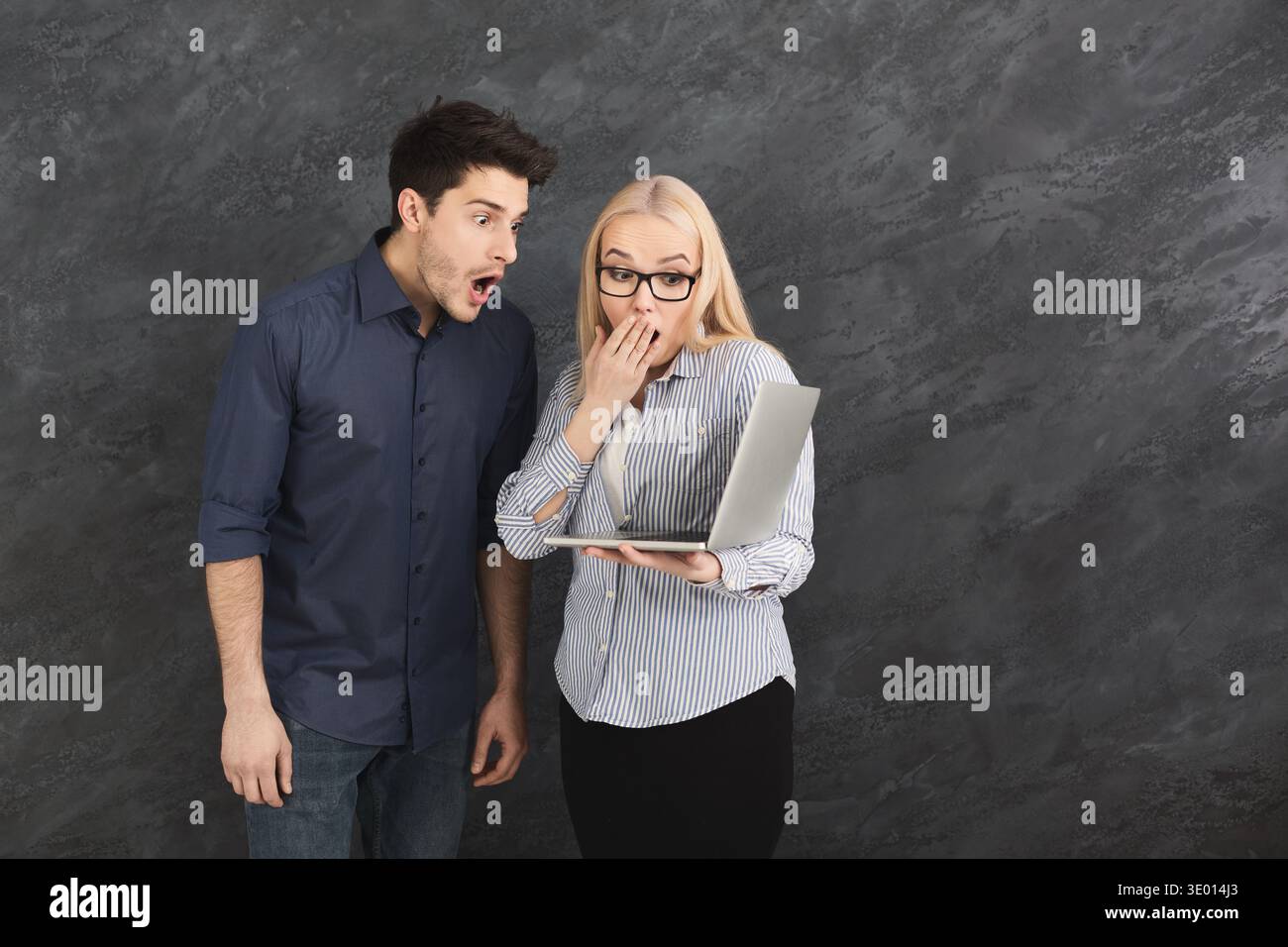 Shocked couple using laptop at studio Stock Photo