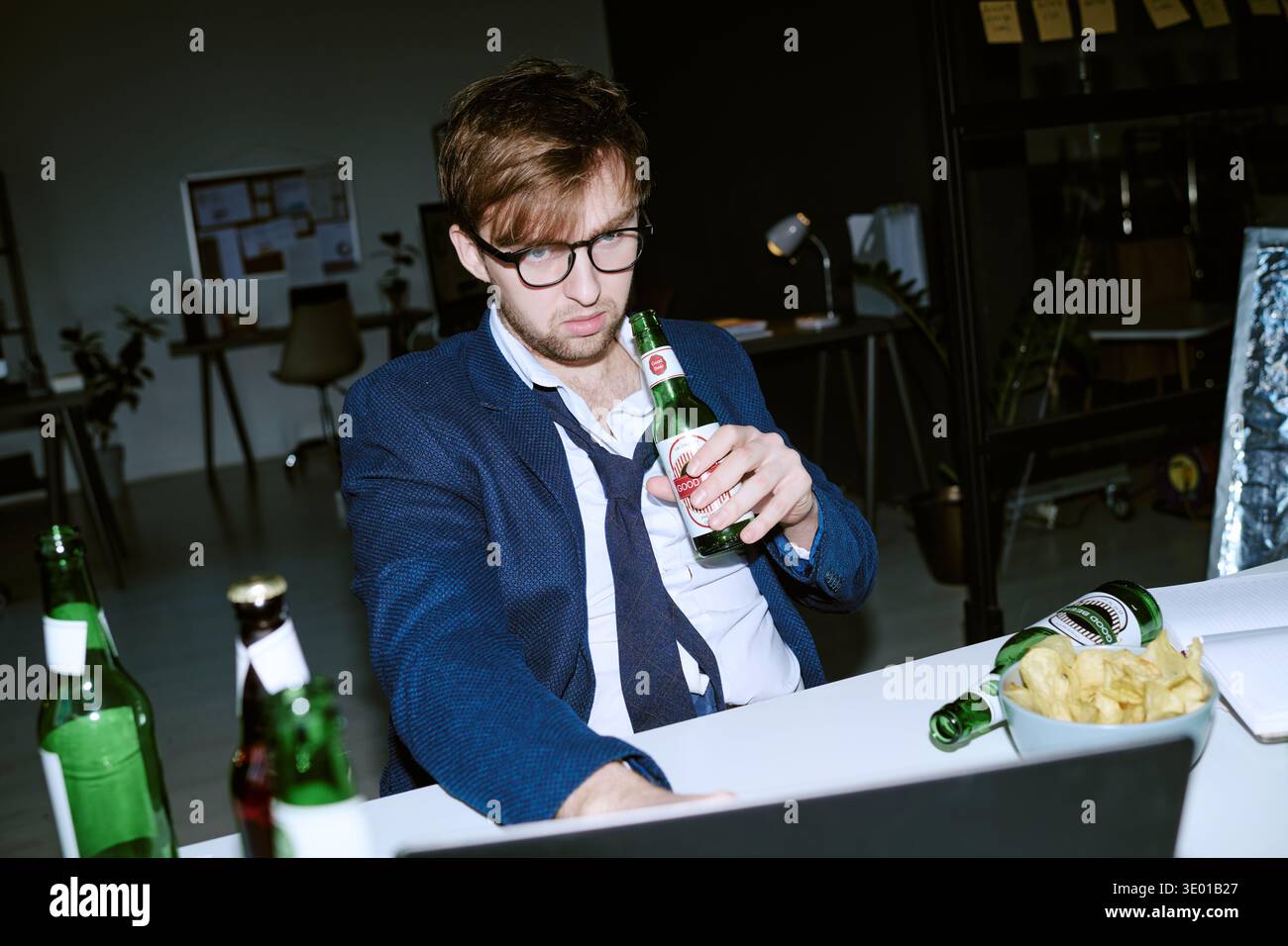 Young Caucasian Man Drinking Beer While Working Late Night in Office Stock Photo