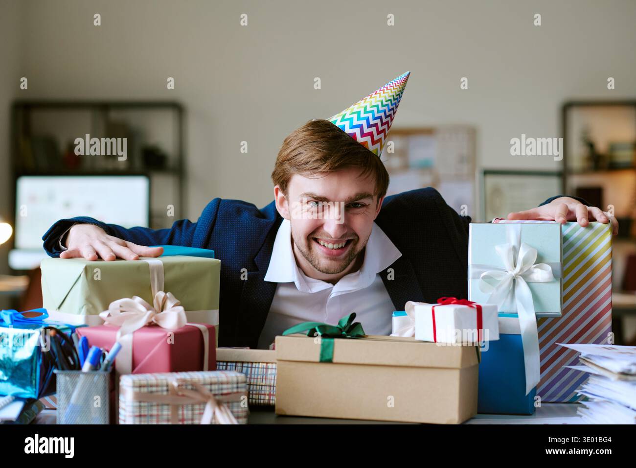 Portrait of Young Caucasian Man Celebrating Birthday Surrounded by Gift Boxes Stock Photo