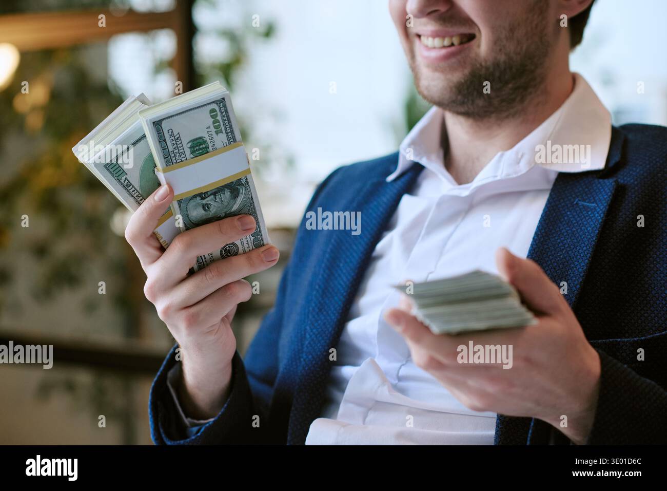 Young Caucasian Man Smiling While Holding Large Stack of Dollar Banknotes Stock Photo
