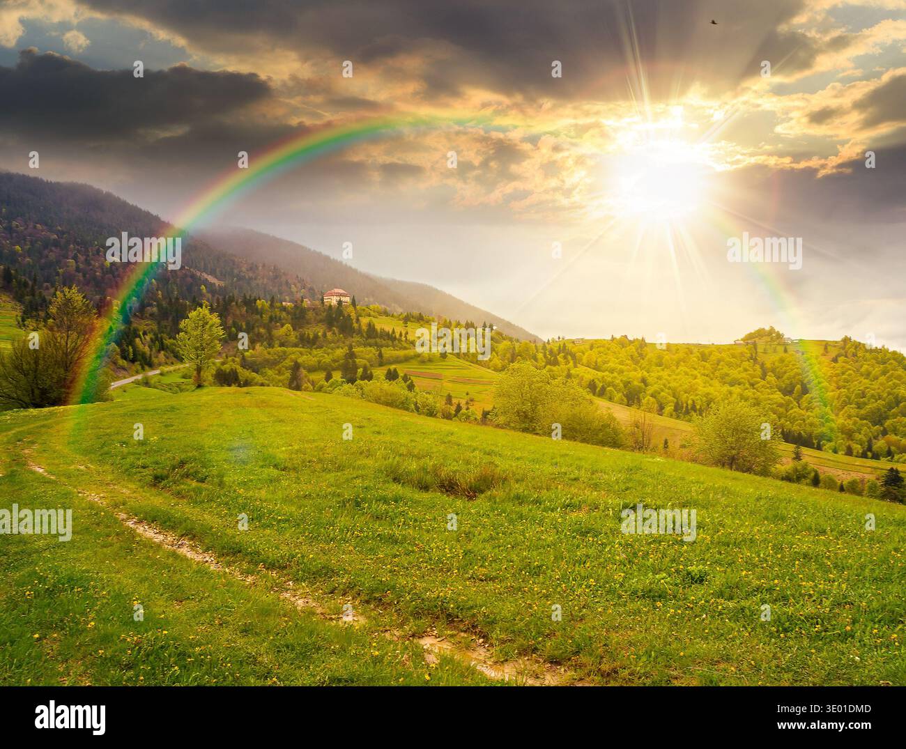 remote countryside in mountain landscape at sunset. hazy weather during spring in evening light. dirt road through lush green pasture on a hill. alpin Stock Photo