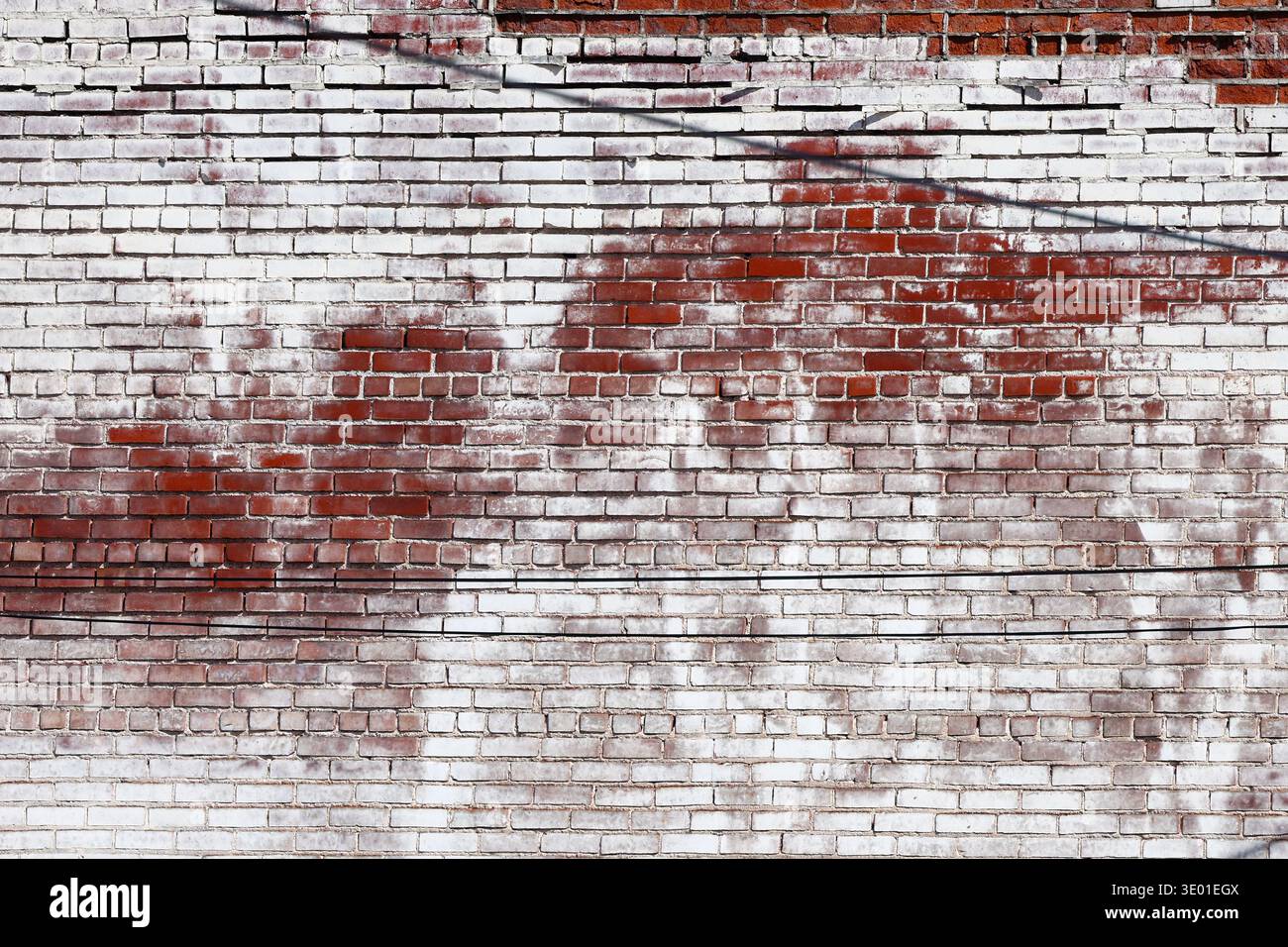 Aged red brick wall with distressed, peeling white paint and weathered texture. Authentic vintage masonry in Menomonie, Wisconsin, USA. Stock Photo